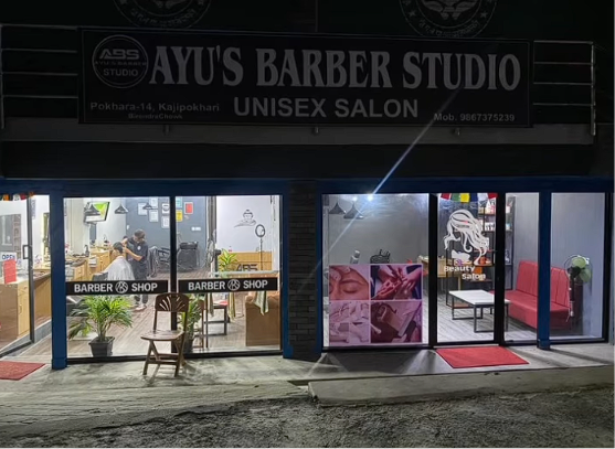 Ayu's Barber Studio wide storefront at night showing the unisex salon and beauty studio space