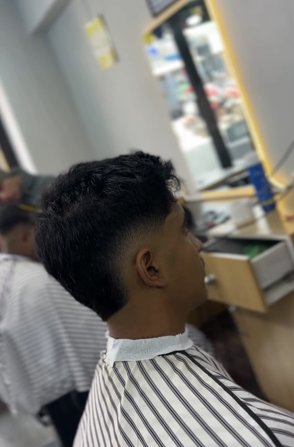 Side back view of a burst fade haircut with textured top