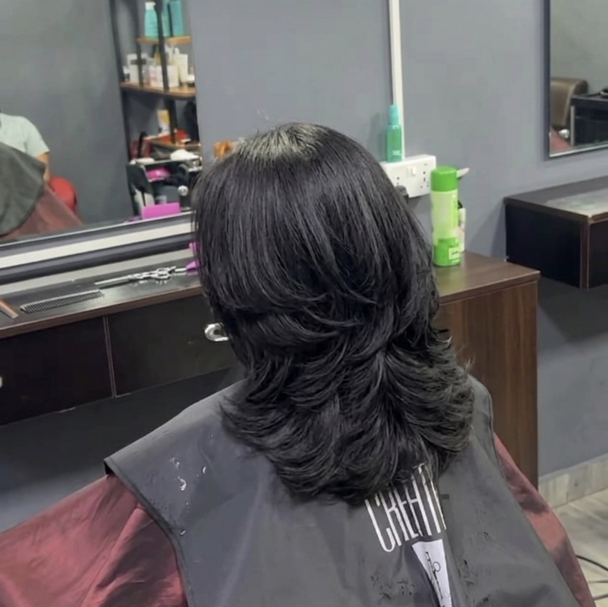 Back view of a volumed layered women's haircut in the salon chair